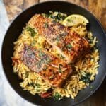 One Skillet Salmon with Lemon Orzo in black pan with lemon slice