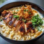 Fiery Chicken Ramen with Creamy Garlic Sauce topped with charred chicken and fresh herbs