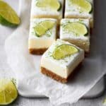 Key lime pie bars on a cutting board with lime wedges