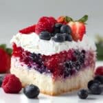 Summer berry poke cake soaked in berry syrup and topped with whipped cream
