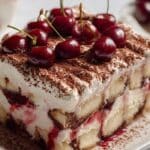 Cherry Amaretto Tiramisu slice topped with fresh cherries and cocoa powder