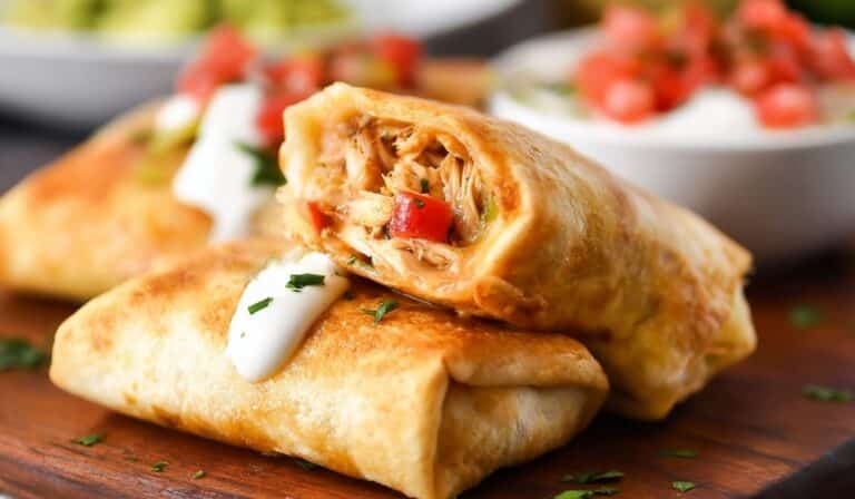 Chicken Chimichangas with golden crispy tortilla filled with shredded chicken and cheese, topped with sour cream