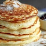 Coconut Cream Pancakes stacked high with toasted coconut on top
