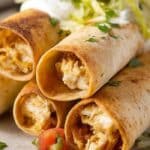 Gluten-Free Chicken Taquitos stacked with shredded lettuce and sour cream