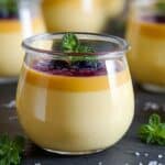 Lemon Panna Cotta in a glass jar with berry sauce, fresh mint, and lemon slices