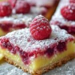 Raspberry Lemon Bars dusted with powdered sugar and topped with fresh raspberries