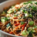 Cold Sesame Noodle Bowls with sesame seeds and vegetables in a white bowl