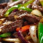 Sizzling Chinese Pepper Steak with Onions in a cast iron skillet