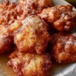 Crispy Sourdough Discard Apple Fritters stacked on a plate dusted with sugar