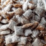 Chex Mix Puppy Chow in a bowl with holiday lights on a rustic table