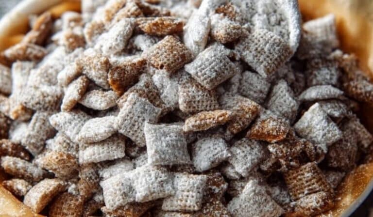 Chex Mix Puppy Chow in a bowl with holiday lights on a rustic table