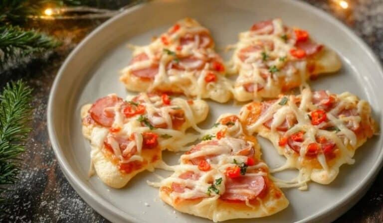 Close-up of a Christmas Tree Mini Pizza served on a white plate with festive toppings