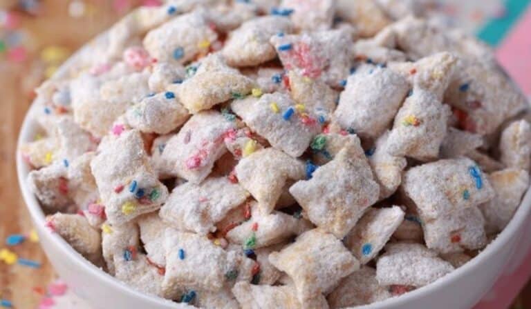 Festive bowl of Cake Batter Puppy Chow on wooden table
