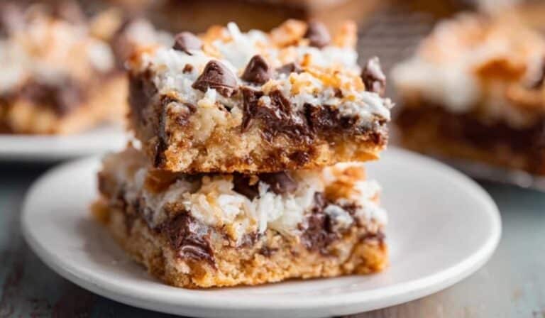 Ultimate Magic Cookie Bars stacked on a white ceramic plate