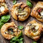 Caprese Pesto Puff Pastry Bites served on a rustic wooden board