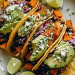 Black bean and sweet potato tacos with cabbage slaw and avocado on a platter.
