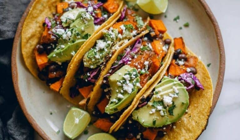 Black bean and sweet potato tacos with cabbage slaw and avocado on a platter.