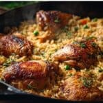 : Dutch oven chicken and rice with golden chicken thighs in a cast-iron pot
