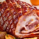 Glazed Easter ham with honey mustard sliced on platter with vegetables