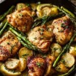 One-pan lemon garlic chicken in a skillet with asparagus and lemon sauce