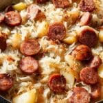 Sauerkraut and sausage skillet with potatoes in a cast iron pan on a rustic table
