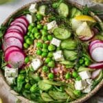 Spring pea and radish grain bowl with farro, peas, radishes, and greens in a ceramic bowl