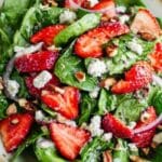 Strawberry spinach spring salad in a large bowl with berries, nuts, and poppy seed dressing
