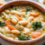White bean and vegetable stew in a Dutch oven with carrots, kale, and creamy beans